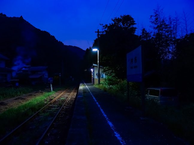 駅前に1軒だけある民家の敷地から焚き火の煙が立ち昇る夕暮れ