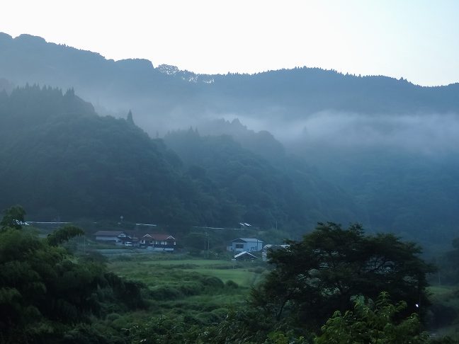 低い丘陵に囲まれた谷間に民家が点在する内名の集落が遠くに見える