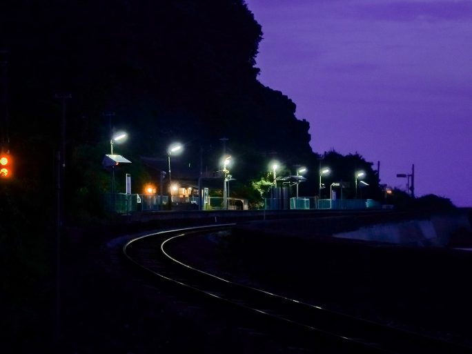 暮色の中に浮かぶ駅の明かりが印象的