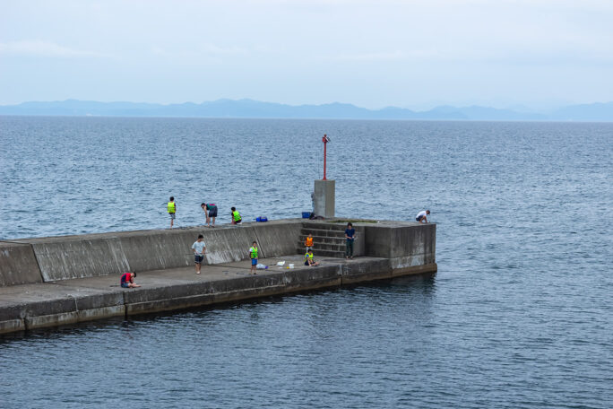 蟹田港の堤防で釣りを楽しむ子供たちを眺めながら出港