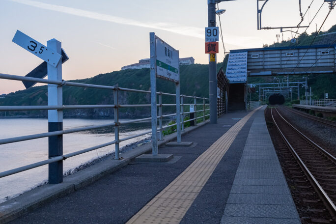 まだ明けやらぬ恋人岬をバックに静かに佇む青海川駅