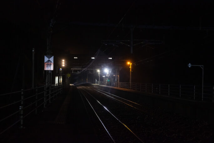 駅に到着する普通列車の前照灯が構内の標識に反射していた