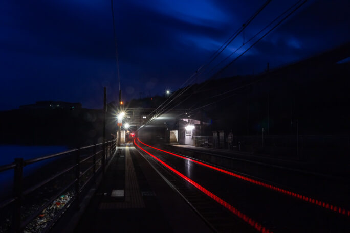 早朝の青海川駅に軌跡を残して貨物列車が走り去る
