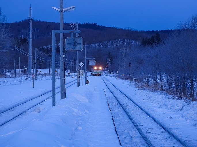 凍てつく寒さの中で列車の到着を待つ