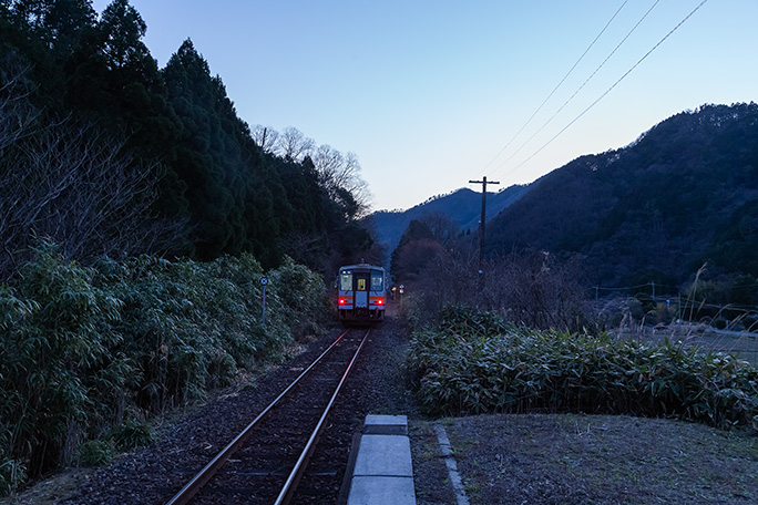 暮れなずむ知和駅を出発していく普通列車を見送る