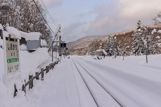 雪にうずもれた駅名標と塩狩駅の全景