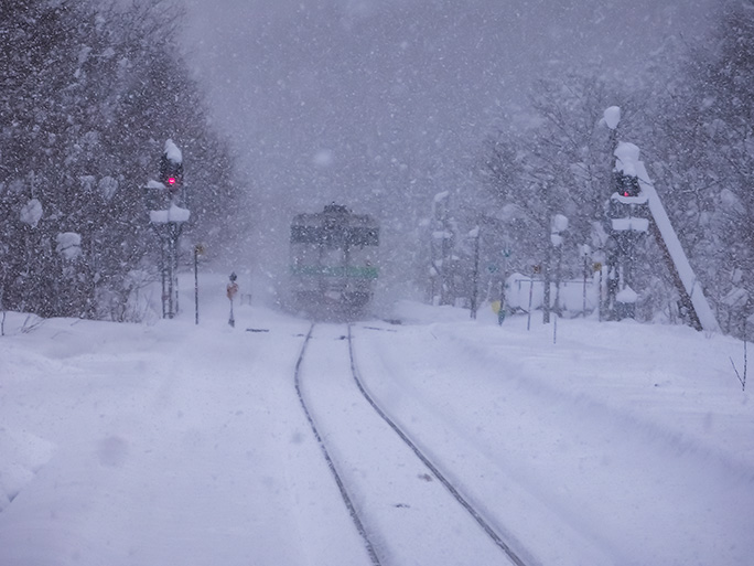 深々と降り積もる雪の中、普通列車は和寒駅に向かって峠の向こうに消えていった