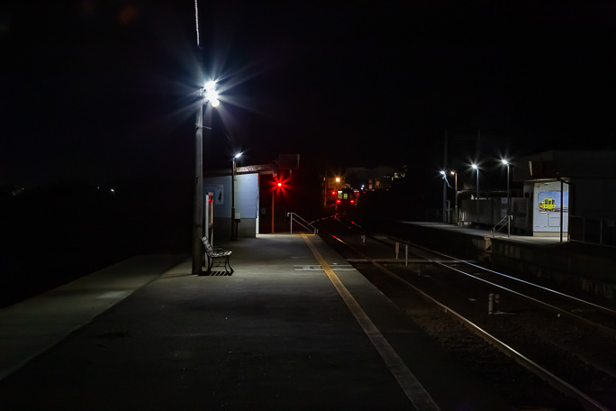 走り去る列車のテールライトを独り見送る旅情駅の夜