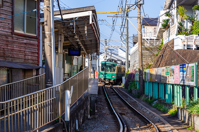 S字カーブの中にある七里ヶ浜駅を普通列車が出発していく