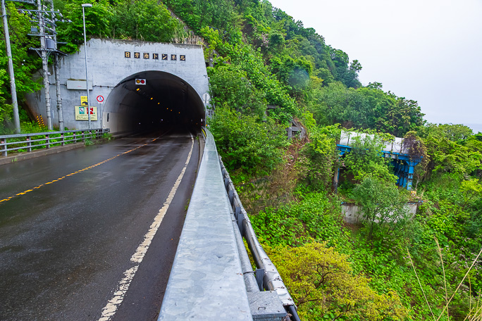現道の日方泊トンネル東側坑口の海側には旧道トンネルの坑口覆いが見えている