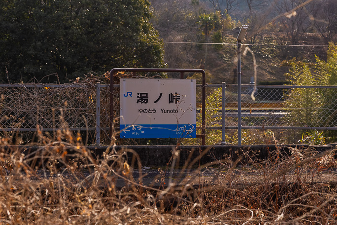 一面の叢となった線路の向こうで二度と来ることのない乗客を待つ駅名標
