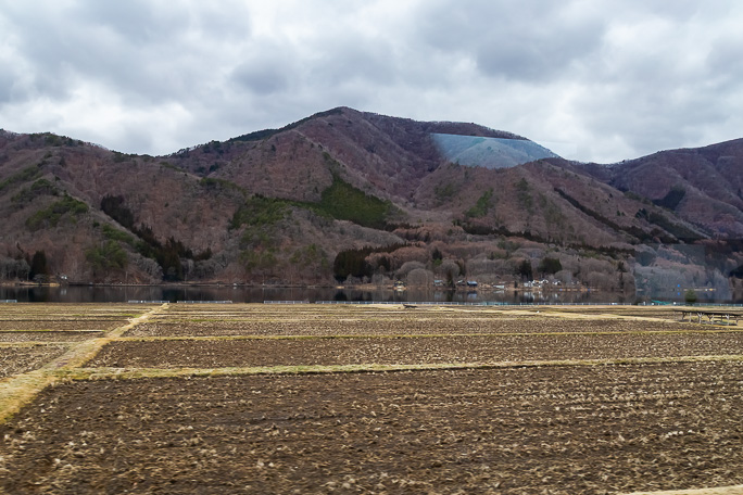 まだ冬枯れの色を纏った早春の木崎湖を大糸線の車窓に眺める